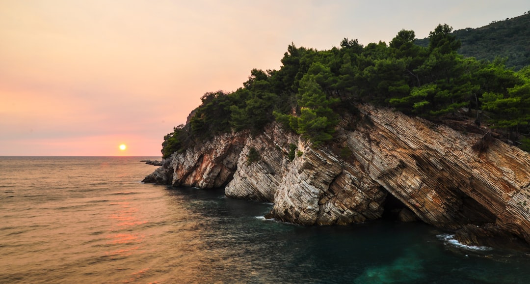 Cyclist riding narrow coastal road Montenegro Adriatic Sea cliffs sunset